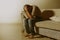 Lifestyle dramatic light portrait of young sad and depressed man sitting at shady home couch in pain and depression feeling stress