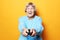 Lifestyle, emotion and people concept: funny grandma is holding a TV remote over yellow background