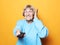 Lifestyle, emotion  and people concept: funny grandma is holding a TV remote over yellow background