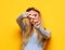 lifestyle, emotion and young people concept: Young woman smiling and show v-sign over yellow background