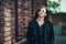 Lifestyle fashion portrait of brunette girl in rock black style, standing outdoors in the city street