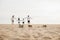 lifestyle father, mother and kids take off shoes running on sand