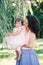 Lifestyle group portrait of smiling white Caucasian brunette mother holding hugging daughter in pink dress