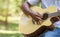 Lifestyle hobbies concept. Hands of guy playing acoustic guitar while sitting on nature background. Handsome man practicing