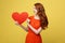 Lifestyle and Holiday Concept - Portrait Young happy red hair woman in orange beautiful dress holding big red heart