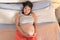 Lifestyle home portrait of young happy and beautiful Asian Korean woman pregnant lying on bed relaxed and excited about maternity