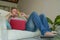 Lifestyle indoors portrait of young happy relaxed and attractive man lying at home sofa couch with headset and laptop listening to