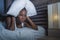 Lifestyle night portrait of young desperate and stressed black african American woman lying on bed upset trying to sleep suffering