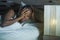 Lifestyle night portrait of young sad and stressed black african American woman lying on bed upset trying to sleep suffering insom