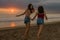 Lifestyle outdoors portrait of two young sisters or Asian Chinese girl at sunset beach with her best friend having fun enjoying S