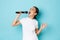 Lifestyle, people and leisure concept. Passionate and carefree pretty asian girl singing song in microphone, bending