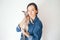 Lifestyle photo of a woman in casual clothes  holding and hugging cute sleepy Devon Rex kitty. Cat is feeling happy and purrs in