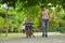 Lifestyle portrait of Asian Indonesian mother and young happy son at city park having fun together the kid learning bike riding