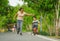 Lifestyle portrait of Asian Indonesian mother and young happy son at city park having fun together the kid learning bike riding