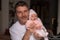 Lifestyle portrait of attractive and happy man holding his baby girl in his arms as a proud father in parenting and love concept