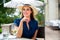 Lifestyle portrait headshot of a beautiful and elegant caucasian woman sitting at a patio cafe outside, near a countryside park or