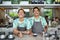 Lifestyle portrait of two friendly smiling balinese millennial baristas wearing trendy clothing and aprons in hipster