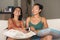 Lifestyle portrait of two young happy and relaxed Asian girlfriends having fun talking laughing and gossiping at home sofa couch s