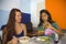 Lifestyle portrait of young attractive hispanic girl sitting at modern cafe having lunch with entrepreneur woman in girlfriends