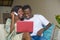 Lifestyle portrait of young happy and attractive black African American couple enjoying at home using credit card and laptop