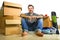 Lifestyle portrait young happy and attractive man unpacking cardboard boxes and belongings moving alone to new apartment in