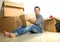 Lifestyle portrait young happy and attractive man unpacking cardboard boxes and belongings moving alone to new apartment in