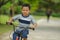 Lifestyle portrait of young happy and excited 5 years old Asian Indonesian child enjoying learning bike at city park isolated on