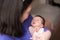 Lifestyle shot on young and happy Asian Chinese woman holding tenderly her adorable newborn baby girl in her arms in mother and