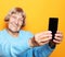 Lifestyle, tehnology and people concept: grandma in blue sweater smiles and takes a selfie