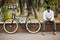 Lifestyle, transport, communication and people concept. Young indian man with bicycle and smartphone on city street