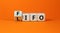 LIFO or FIFO last in first out symbol. Changed concept words LIFO to FIFO on wooden blocks. Beautiful orange table orange