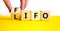 LIFO or FIFO last in first out symbol. Changes concept words LIFO to FIFO on wooden blocks. Beautiful yellow table white