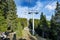 Lift with cable passes between spruce forest on peak against backdrop of mountain ranges of Rhodope Mountains