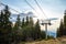 Lift with cable passes between spruce forest on peak against backdrop of mountain ranges of Rhodope Mountains