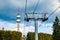 Lift with cable passes between spruce forest on peak against backdrop of mountain ranges of Rhodope Mountains