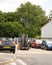 Lift truck coming along a road between parked cars with wooden pallets held in tines