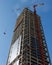 Lifting crane hoisting a weight at skyscraper cons