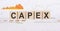 On a light background, graphs, diagrams and wooden cubes with the word CAPEX - Capital Expenditure