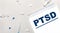 On a light background, a syringe, a stethoscope, vials of medicine, an ampoule and a white notepad with the text PTSD. Medical