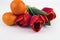 Light background with tangerines, lemon and tulips on a white plate