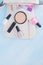 On a light background, from a white cosmetic bag, scattered items for manicure and makeup, light eyeshadow, brushes , face powder