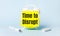 On a light blue background - a white handle and an alarm clock with a bright yellow sticker glued to it with the text TIME TO