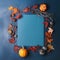 Light blue blank sheet in frame of pumpkins, leaves, twigs, berries on blue textured background.
