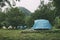 Light blue color dome tent and mountain range landscapes in the background. Tourist camp with lots of tents in the woods