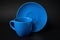 Light blue cup of coffee and saucer on a black background