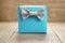 Light blue gift box with minimalistic silver ribbon bow on wooden