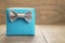 Light blue gift box with minimalistic silver ribbon bow on wooden