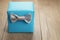 Light blue gift box with minimalistic silver ribbon bow on wooden table