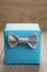 Light blue gift box with minimalistic silver ribbon bow on wooden table