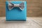 Light blue gift box with minimalistic silver ribbon bow on wooden table